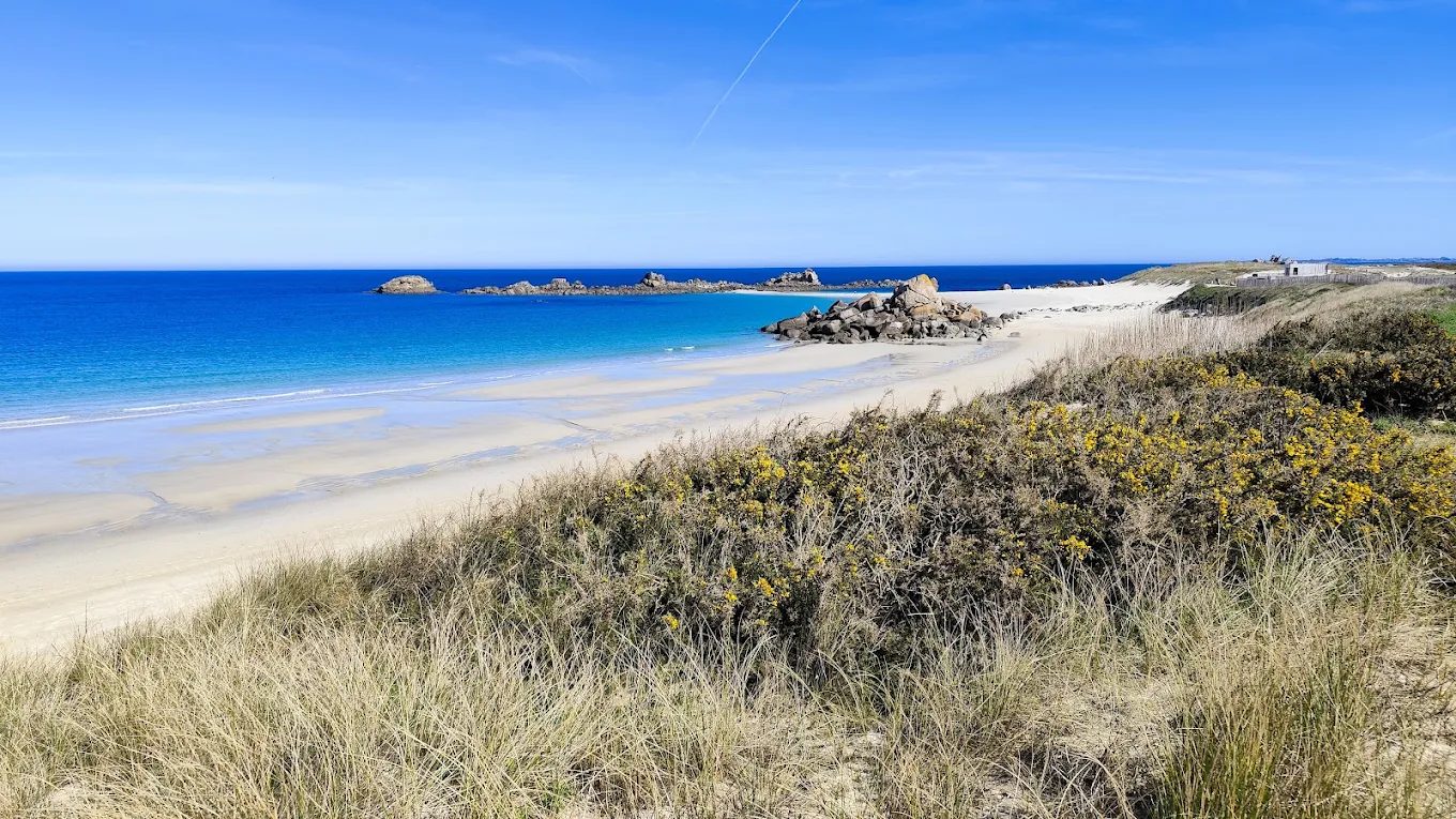 Vue d'ensemble de la plage des Amiets a Cleder avec ses eaux turquoise et ses baigneurs